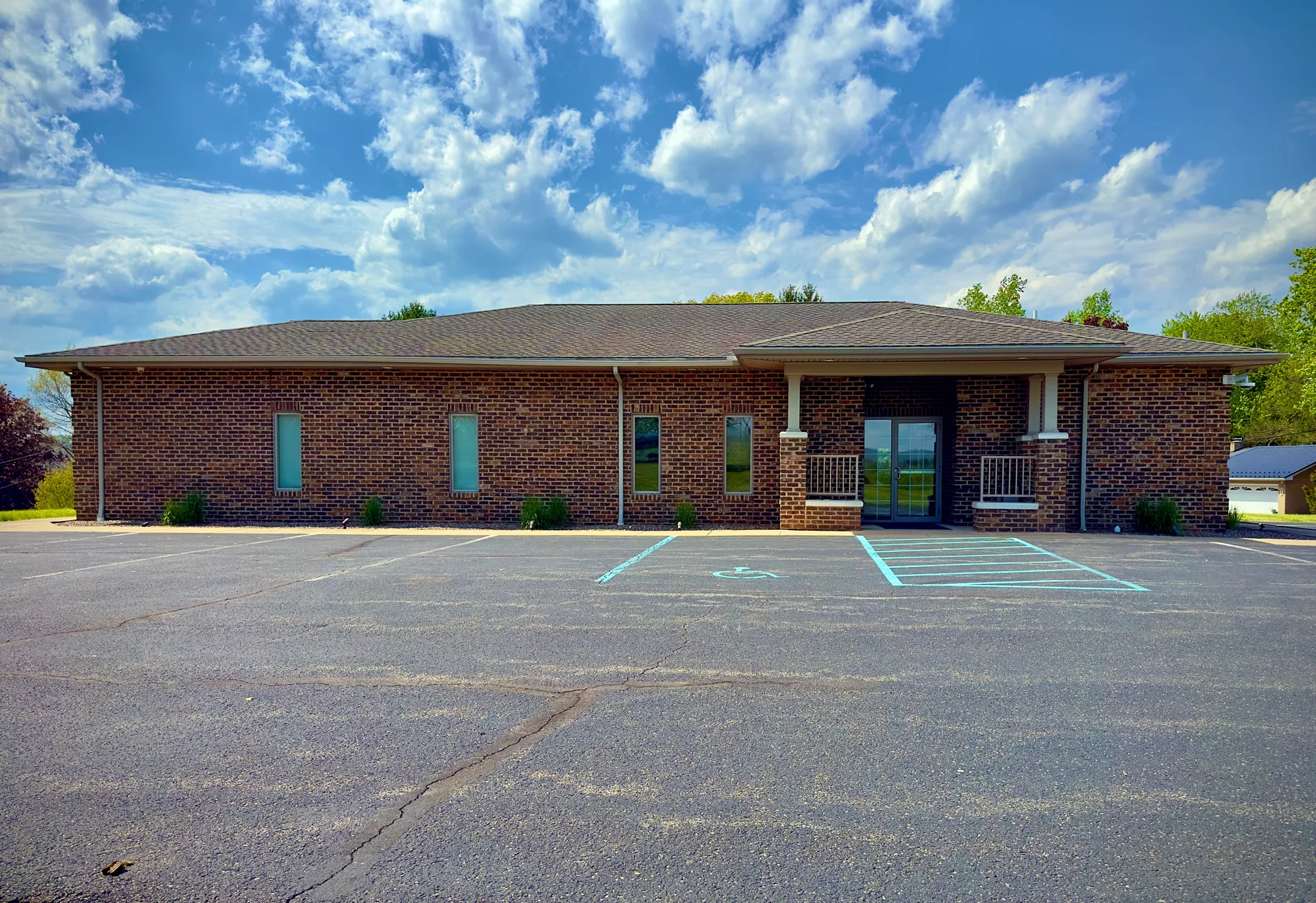 Red brick commercial building with sunny, accessible parking lot.